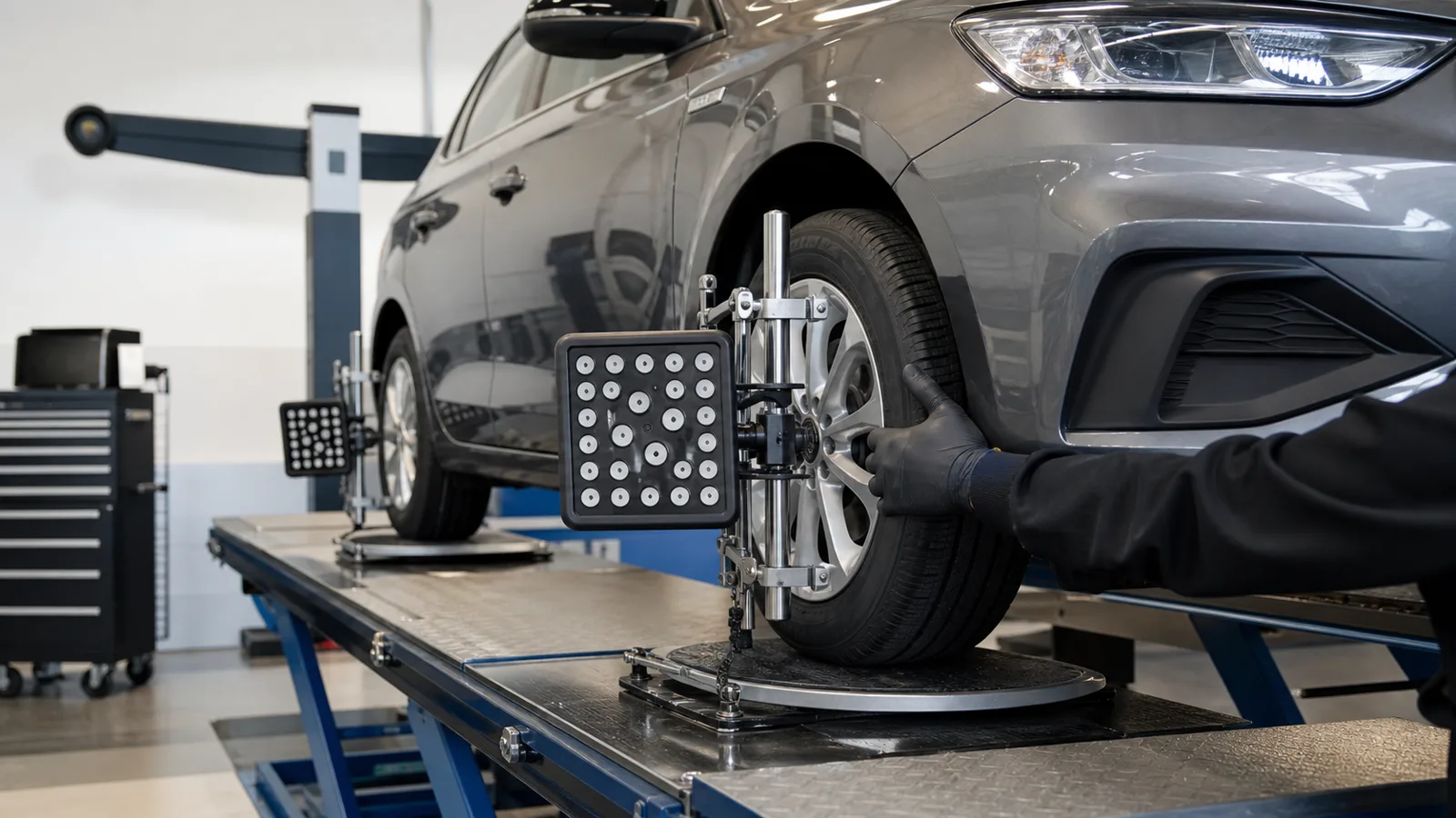 Mechaniker richtet Messsensor an einem Pkw-Rad zur Achsvermessung aus